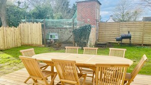 Une terrasse en bois avec une table ronde et six chaises.
