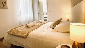 Une chambre d’hôtel comprenant un lit, une lampe de chevet, un luminaire fixé au mur et une porte donnant accès à une salle de bain.
