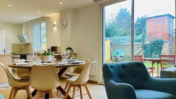 Une cuisine moderne avec un coin repas, de grandes fenêtres et une vue sur le jardin.