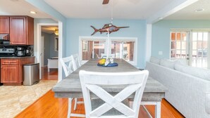 A dining area with a wooden table, white chairs, and a ceiling fan. - Waterfront 3BR Villa w/ Gym/Pool & Dock Access (Riverview)