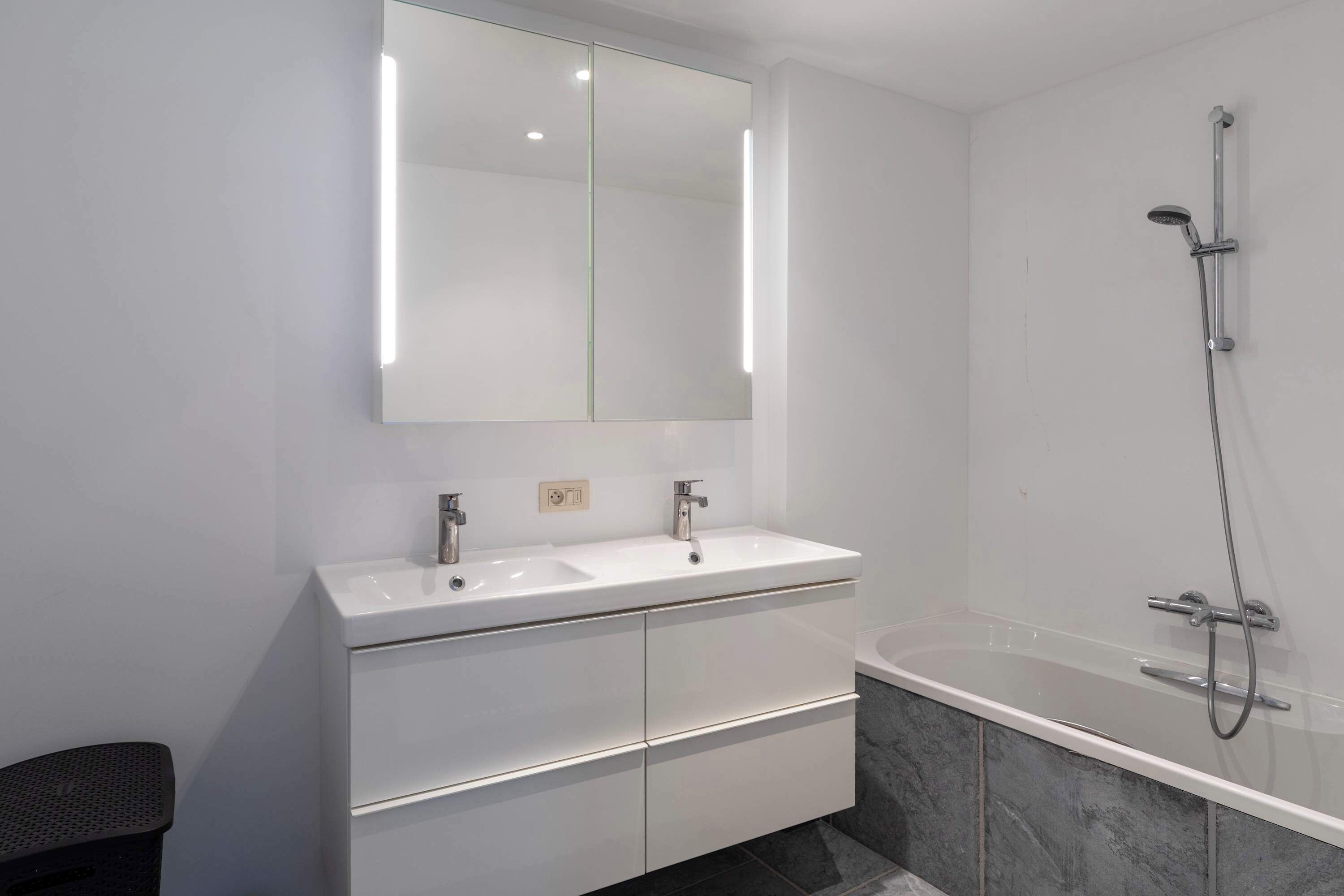 Een moderne badkamer met een dubbele wastafel, een grote spiegel en een inloopdouche.