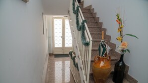 Eine Treppe mit weißer Geländer, eine große Vase mit Blumen und eine Flasche auf den Stufen.