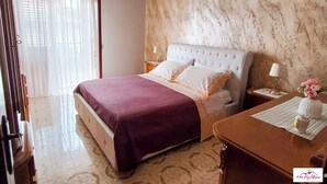 Ein Hotelzimmer mit einem großen Bett, einem Nachttisch, einem Schreibtisch und einer Chandelüster.