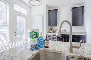 A kitchen with a stainless steel sink, dark cabinets, and a window with blinds. - New, Luxury 3B+Rooftop & Garage - 5 min to UC Hospital, Downtown (Cincinnati)