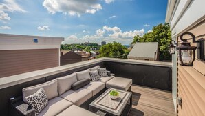 Une terrasse sur le toit aménagée avec un ensemble de canapés, une petite table ornée d’une plante et des lanternes décoratives.