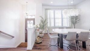 Un coin repas avec une table ronde et six chaises, un lustre et une plante en pot.