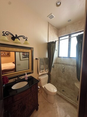 A bathroom with a vanity, sink, mirror, toilet, shower, and a window. - Guest bedroom located outside luxury home (Tucson)