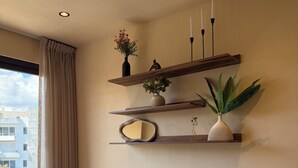A modern living room with a sofa, decorative shelves, and a large window. - 10 min. from beach, New luxury condo w/ Pool, Gym, Sauna, Parking and laundry! (Playa del Carmen)