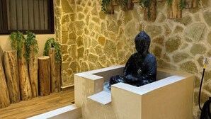 A modern indoor space with a stone wall, wooden planters with greenery, and a black statue in a bathtub. - 10 min. from beach, New luxury condo w/ Pool, Gym, Sauna, Parking and laundry! (Playa del Carmen)