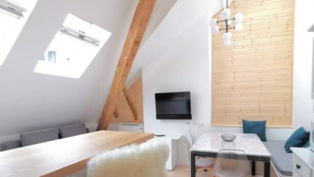Ett modernt rum i loftstil med ett sluttande tak, takfönster, en matplats och ett kök.