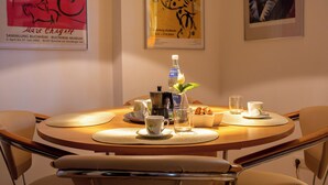A dining area with a round table, chairs, a coffee machine, cups, and a bottle of water. - Strandvilla Hubertus - H1 - Marc Chagall (Ostseebad Boltenhagen)