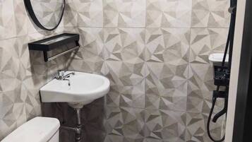 A compact bathroom with a toilet, sink, and shower.