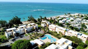 A coastal resort with multiple buildings, a central swimming pool, and a view of the ocean. - Oceanfront Escape 3BR 2BA Pool Parking Private Beach Access Loíza (Loíza)