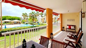 A balcony with a view of a swimming pool, a wooden table, and a bench. - Oceanfront Escape 3BR 2BA Pool Parking Private Beach Access Loíza (Loíza)