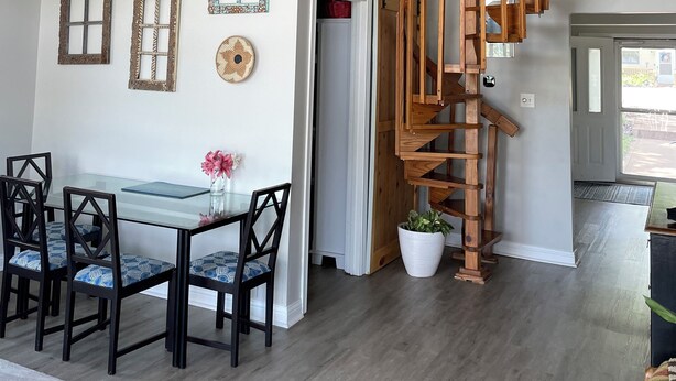 A dining area with a glass table and chairs, a ceiling fan, and a wooden staircase leading to an upper level.