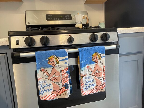 A kitchen with a stove, oven, and two towels hanging from the oven handle.