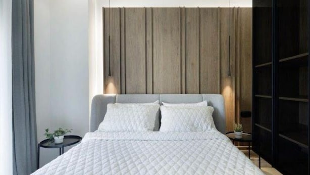 A modern bedroom with a large bed, a wooden headboard, and a small bedside table with a plant. - Plaza Luxury Suite | 2’ from Metro | 5’ from Piraeus (Koridallos)