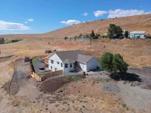 A single-story house with a gabled roof, surrounded by a fenced yard. - Ranch Retreat Sleeps 16 VIEWS Hot tub Gas Firepit (Ellensburg)