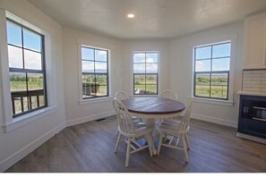 A dining area with a round table and four chairs, large windows with a view of the outdoors, and a fireplace. - Ranch Retreat Sleeps 16 VIEWS Hot tub Gas Firepit (Ellensburg)