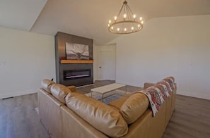 Ein geräumiges Wohnzimmer mit einer Ledersofa, einem Kamin und einer Chandelier.