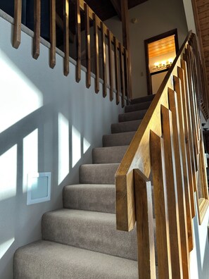 A staircase with wooden railings and carpeted steps. - Green Mountain Getaway (Munds Park)