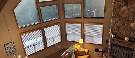 A spacious living room with a stone fireplace, large windows, and a cozy seating area.