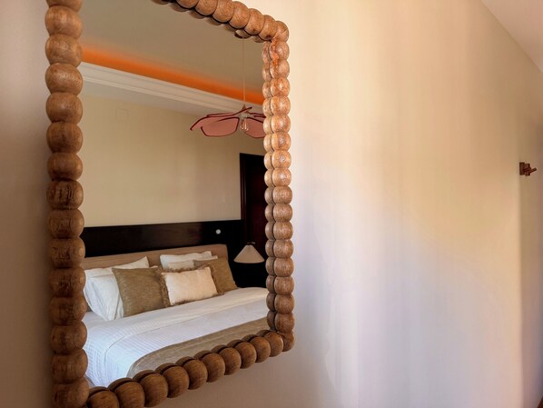 A bedroom with a large mirror, a bed with white linens, and a nightstand with a lamp. - CASABA - Boutique - Torre del Mar (Torre del Mar)