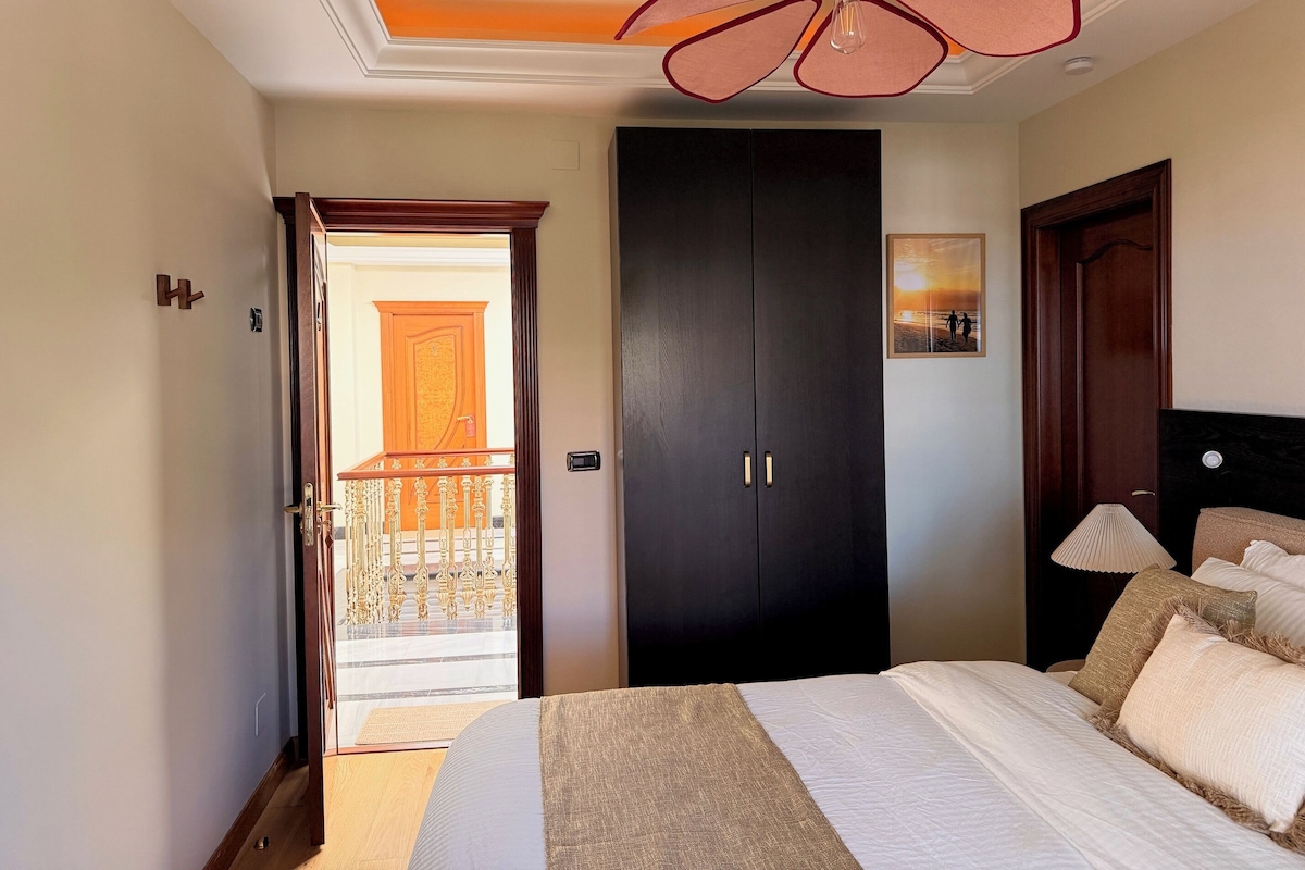 A hotel room with a bed, a dark wardrobe, a ceiling fan, and a balcony door.