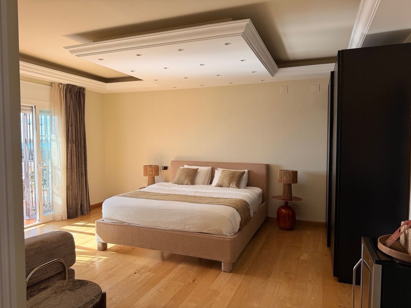 Une chambre à coucher avec un grand lit, deux lampes de chevet, un plancher en bois et une vue par la fenêtre.