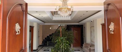 Um amplo salão com lustre, escadaria e área de recepção.