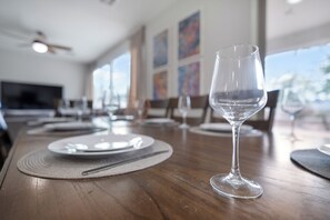 A dining table with plates, cutlery, and a wine glass set in a modern dining area with large windows and artwork on the walls. - Westgate Retreat, Family & Pet-Friendly 4BR Home (Glendale)
