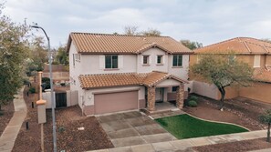 A two-story house with a tiled roof, a garage, and a small front yard with a lawn and a tree. - Westgate Retreat, Family & Pet-Friendly 4BR Home (Glendale)