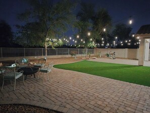 An outdoor patio area with a brick floor, green artificial turf, and outdoor furniture. - Westgate Retreat, Family & Pet-Friendly 4BR Home (Glendale)