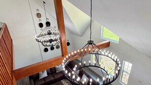 Ett rum i loftstil med en trätrappa, en kristallkrona, en soffgrupp och utsikt över omgivningarna.