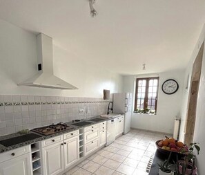 A kitchen with white cabinets, a gas stove, a sink, and a window with a view.