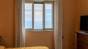 A bedroom with a bed, a dresser, and a window with curtains. - Large Apartment with Sea View and Parking in the center of Acireale. (Acireale)