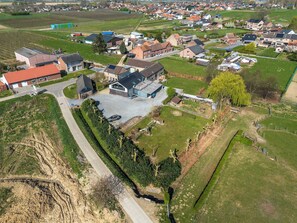 An aerial view of a residential area with houses, a large building with a garage, and surrounding fields.