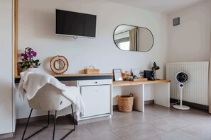 A hotel room with a desk, chair, television, mirror, radiator, fan, and a small basket. - Boutique hotel het Zoete Zijn Borgloon - Suite 2 (Tongeren-Borgloon)