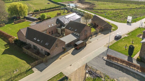 A rural property with multiple buildings, including a main house with a large garage and a smaller adjacent structure. - Boutique hotel het Zoete Zijn Borgloon - Suite 2 (Tongeren-Borgloon)