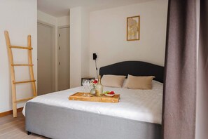 Ein ordentlich gemachtes Bett mit Tablett mit Speisen und Getränken, eine Holzleiter und ein gerahmtes Bild an der Wand.
