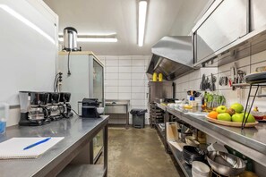 Una cuina moderna amb electrodomèstics d'acer inoxidable, una màquina de cafè i una varietat d'utensilis i recipients de cuina.