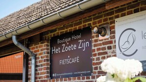 A brick building with a sign for Boutique Hotel Het Zoete Zijn and a Fietscafé.