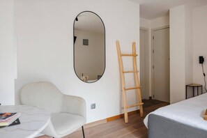 Une pièce comprenant un lit, une chaise, une table, un miroir et une échelle en bois.