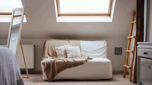 A loft-style bedroom with a high ceiling, a skylight, a white sofa, a wooden ladder, and a white dresser. - Boutique hotel het Zoete Zijn Borgloon - Suite 4 (Tongeren-Borgloon)