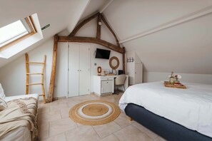 A bedroom with a sloped ceiling, a bed, a desk, a chair, and a TV. - Boutique hotel het Zoete Zijn Borgloon - Suite 4 (Tongeren-Borgloon)