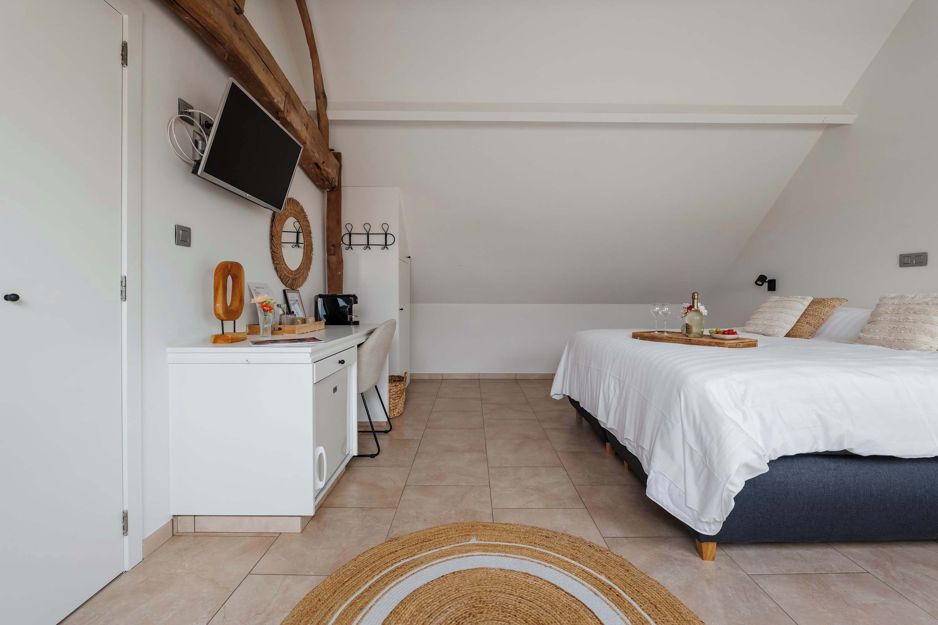 A bedroom with a bed, bedside table, and a TV mounted on the wall.