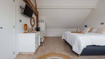 A bedroom with a bed, bedside table, and a TV mounted on the wall.