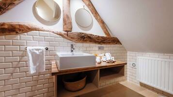 A bathroom with a white sink, wooden vanity, two round mirrors, and a towel rack.