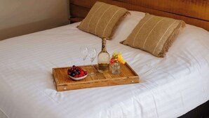 A neatly made bed with a wooden tray holding a bottle, glasses, and a bowl of fruit. - Boutique hotel het Zoete Zijn Borgloon - Suite 3 (Tongeren-Borgloon)