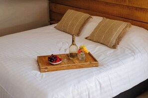 A neatly made bed with a wooden tray holding a bottle, glasses, and a bowl of fruit. - Boutique hotel het Zoete Zijn Borgloon - Suite 3 (Tongeren-Borgloon)